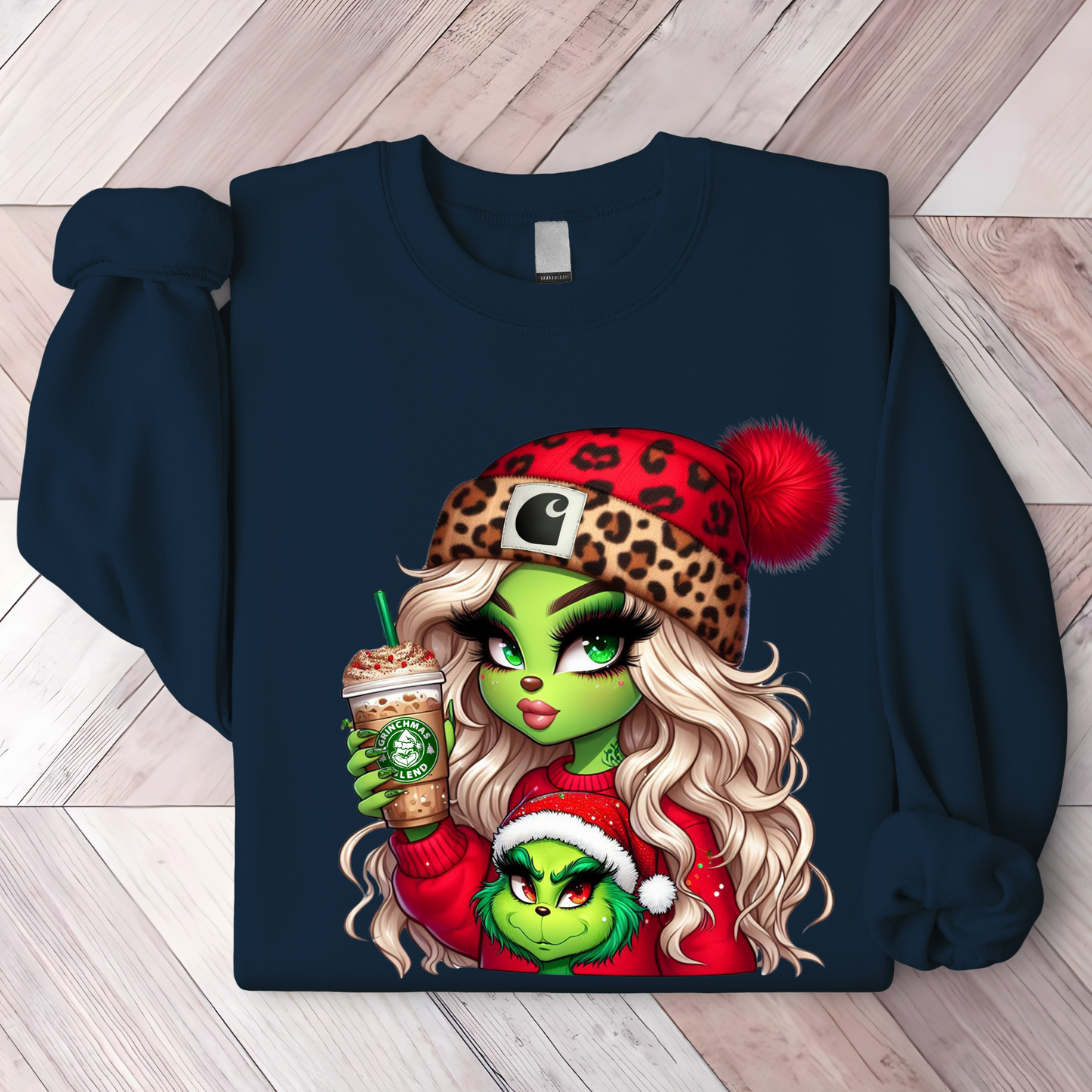 Navy holiday shirt with a festive design of a green holiday girl sipping a seasonal drink next to a mini green buddy in a Santa hat.