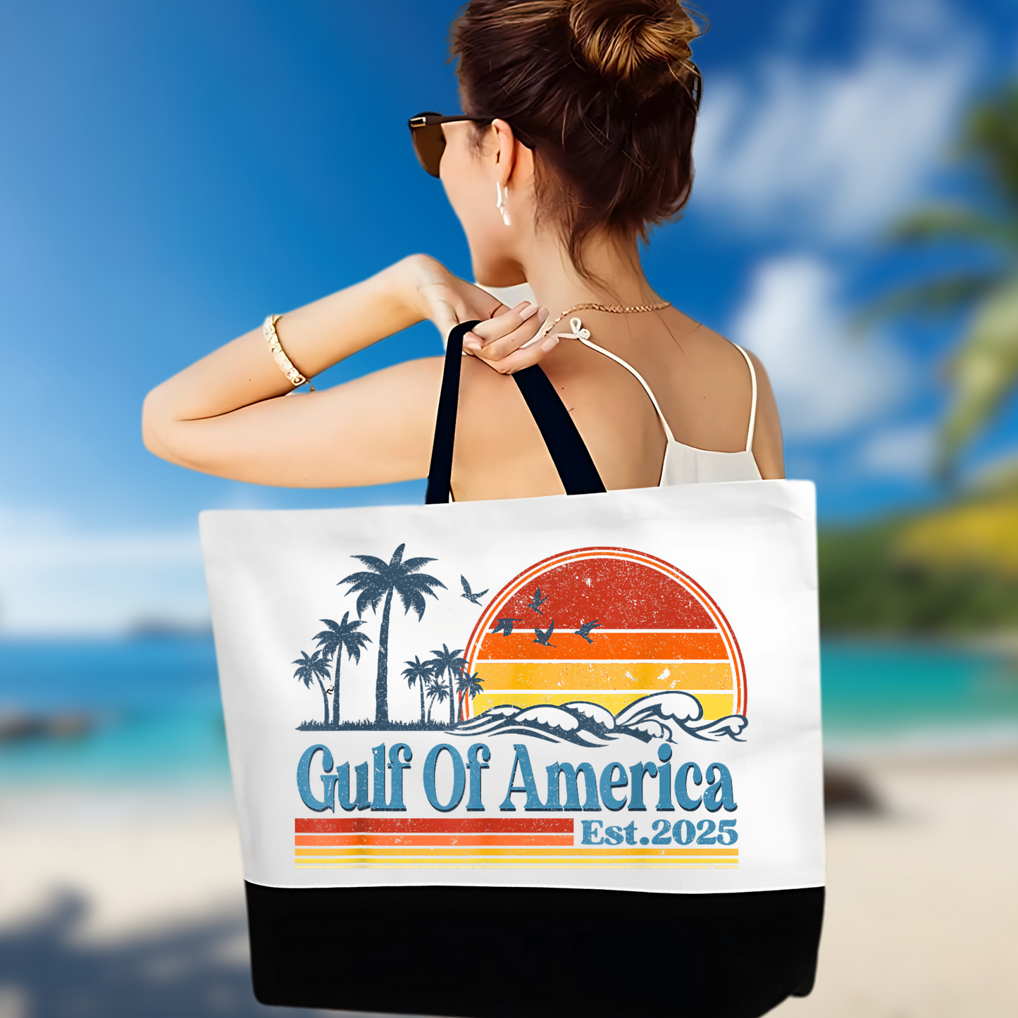 Woman holding a Gulf of America Est. 2025 patriotic beach tote with sunset and palm tree design, standing by ocean in summer dress