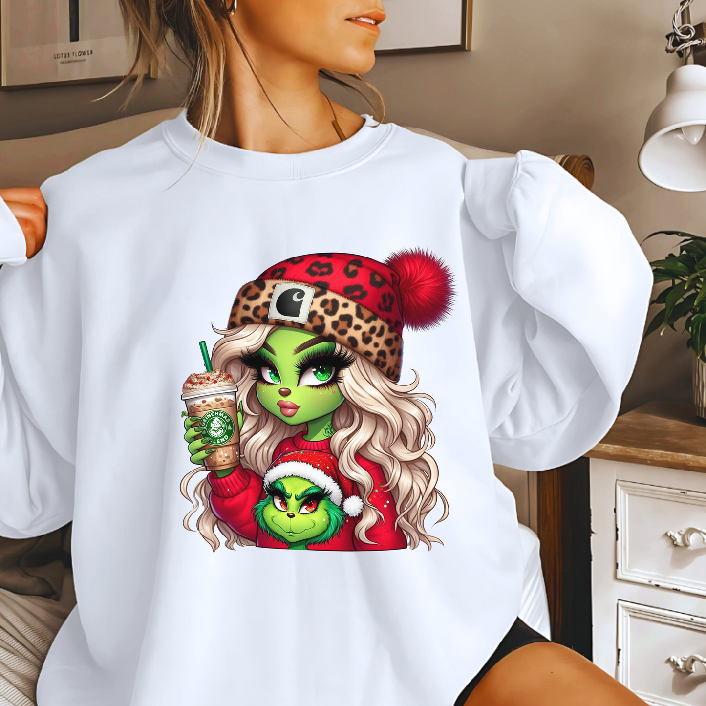 White holiday sweatshirt featuring a glam green girl in a leopard Santa hat holding a festive drink, paired with a cute green character in red.