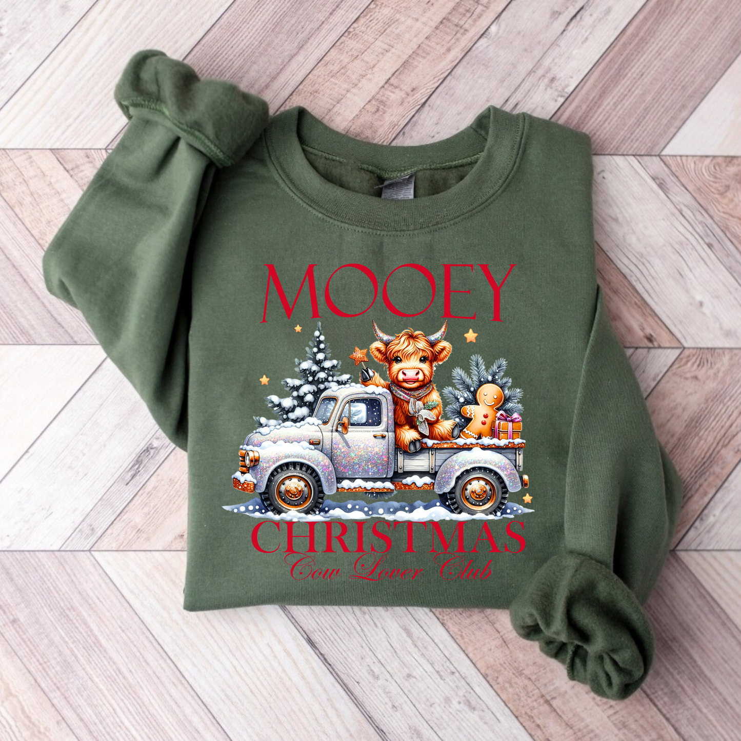 Green folded sweatshirt featuring festive cow in glitter truck