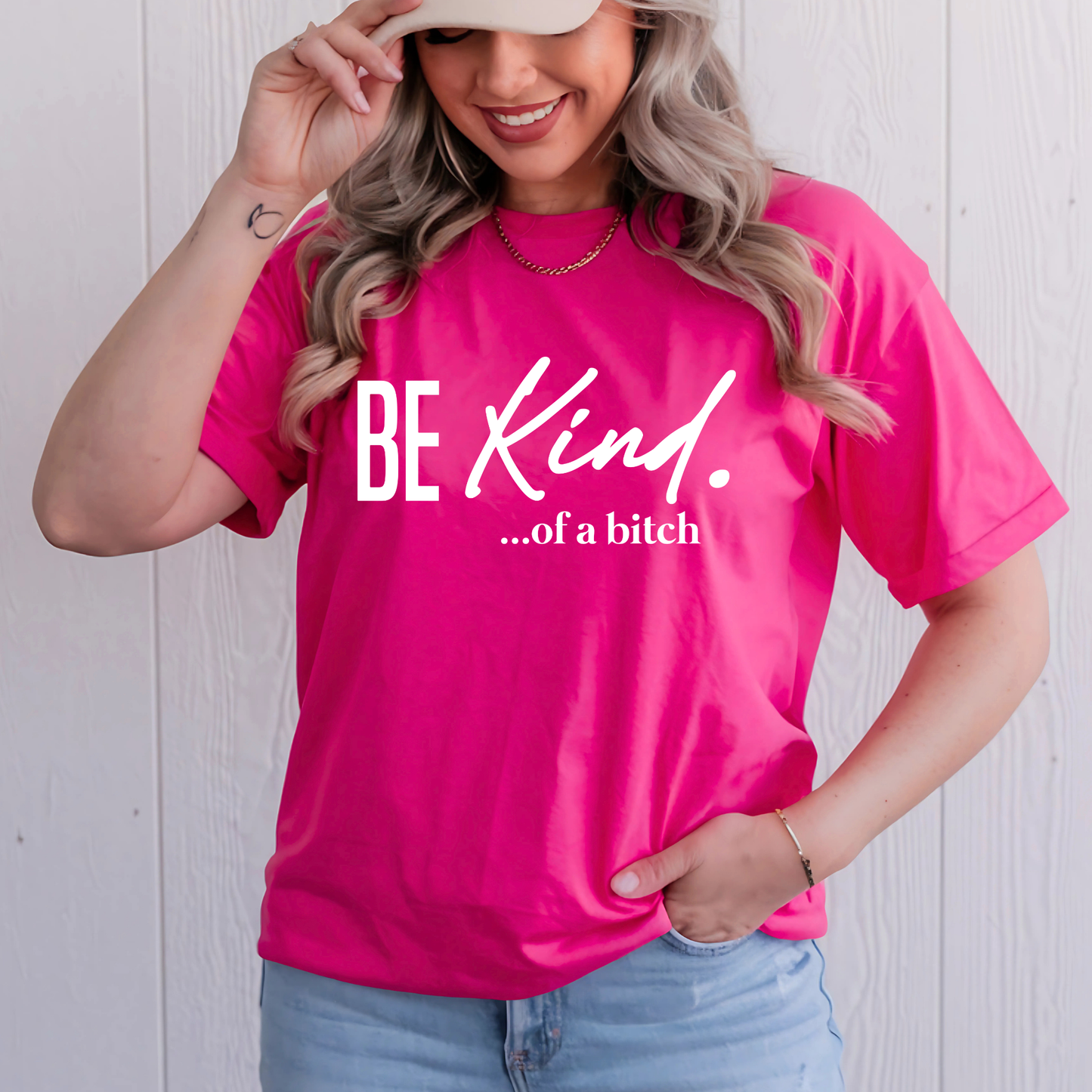 Dark pink T-shirt with “Be Kind…of a bitch” design worn by a cheerful woman