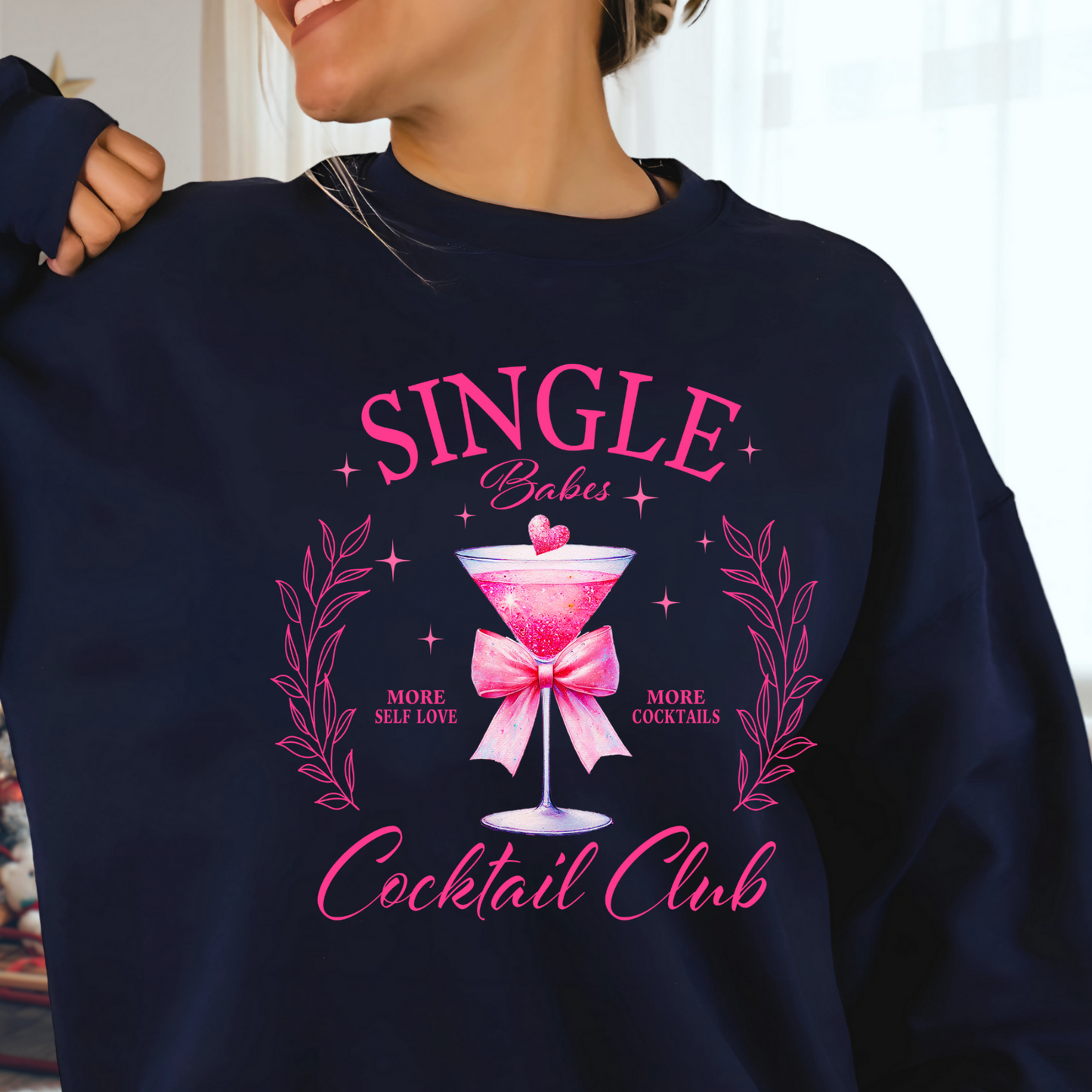 A woman wearing a blue sweatshirt with the text 'SINGLE Babes Cocktail Club' in pink design.