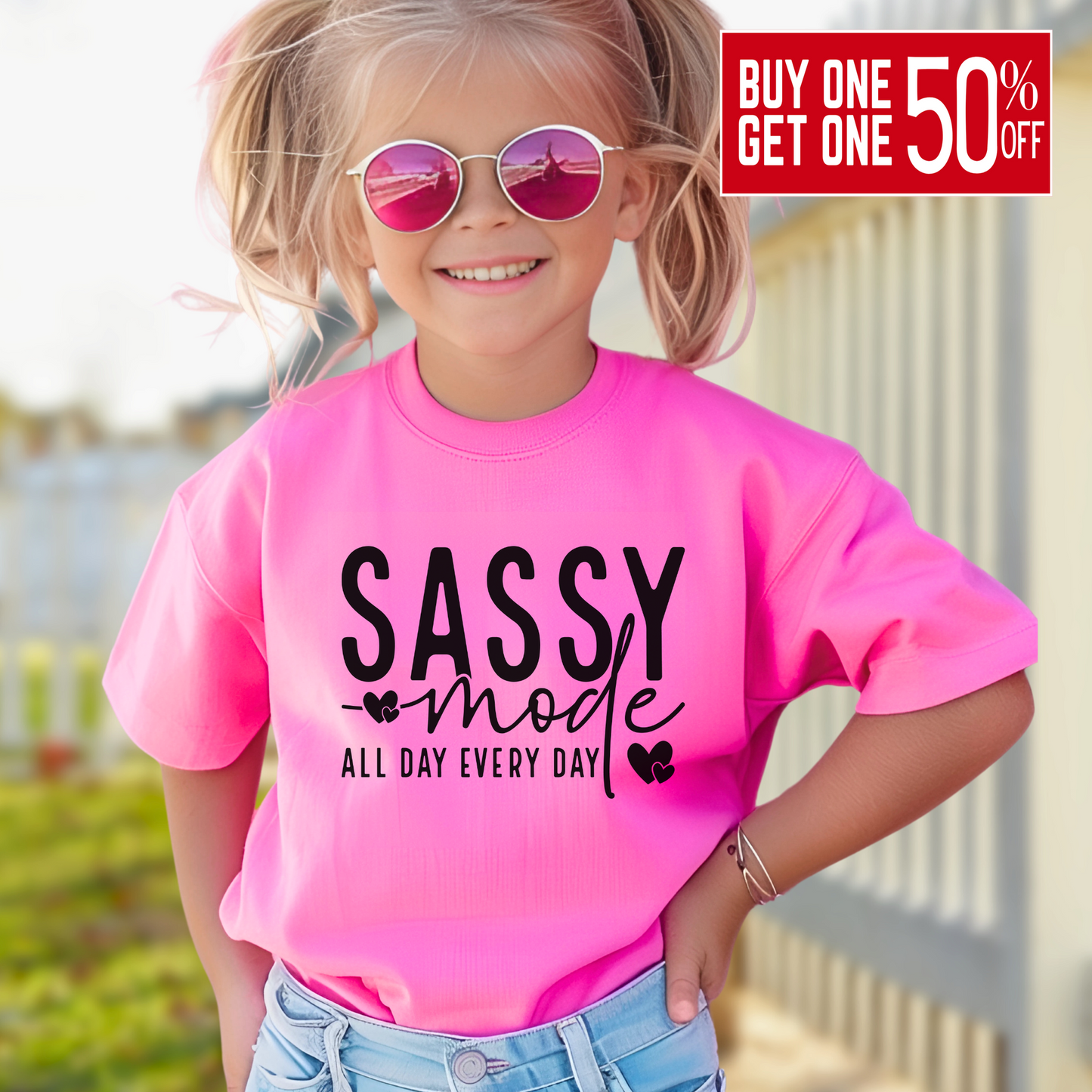 oung girl wearing a navy bright Pink "Sassy Mode – All Day Every Day" graphic t-shirt, smiling confidently outdoors