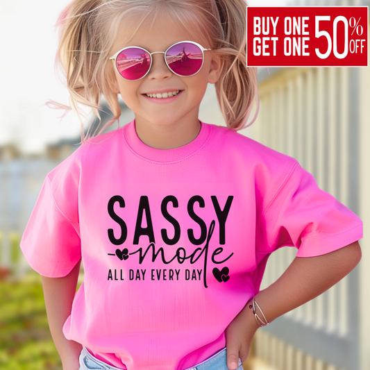 oung girl wearing a navy bright Pink "Sassy Mode – All Day Every Day" graphic t-shirt, smiling confidently outdoors