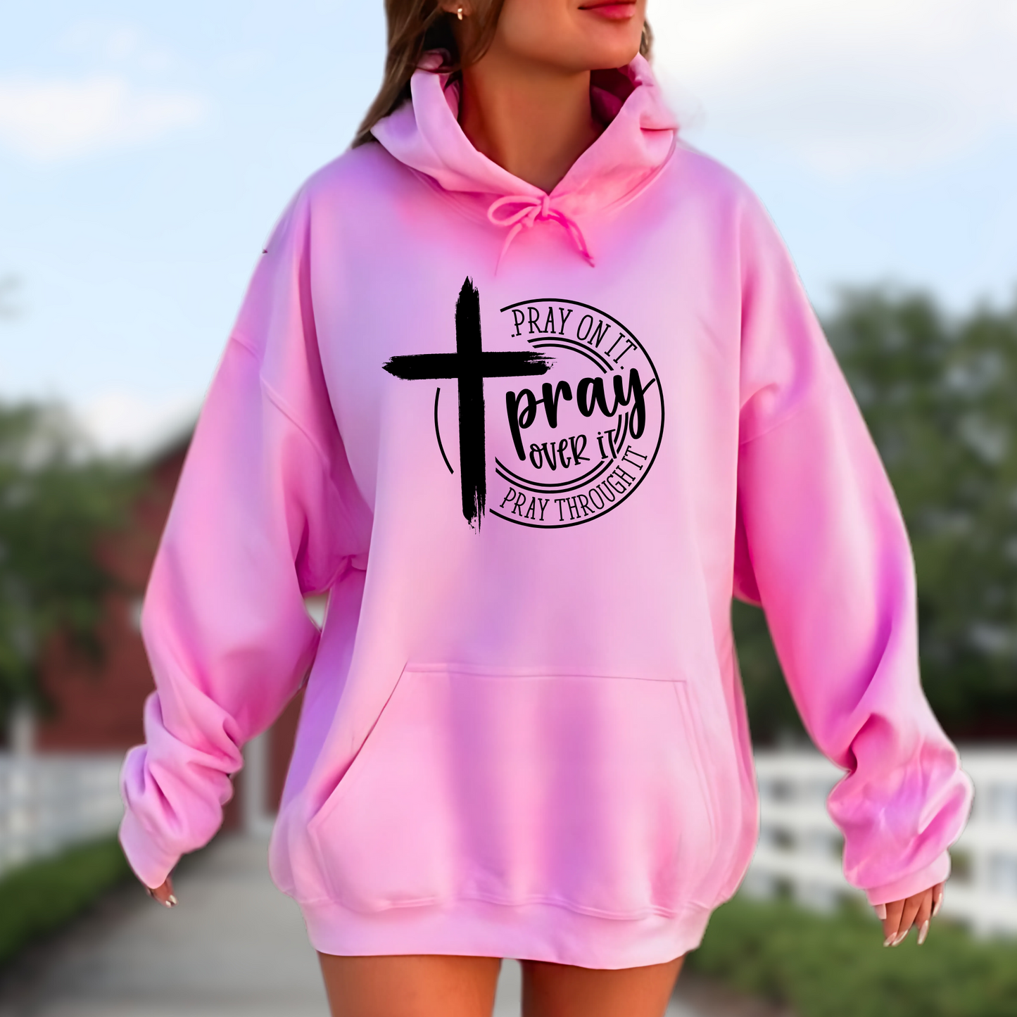Woman wearing a bright pink Christian hoodie with a motivational prayer message and cross symbol.