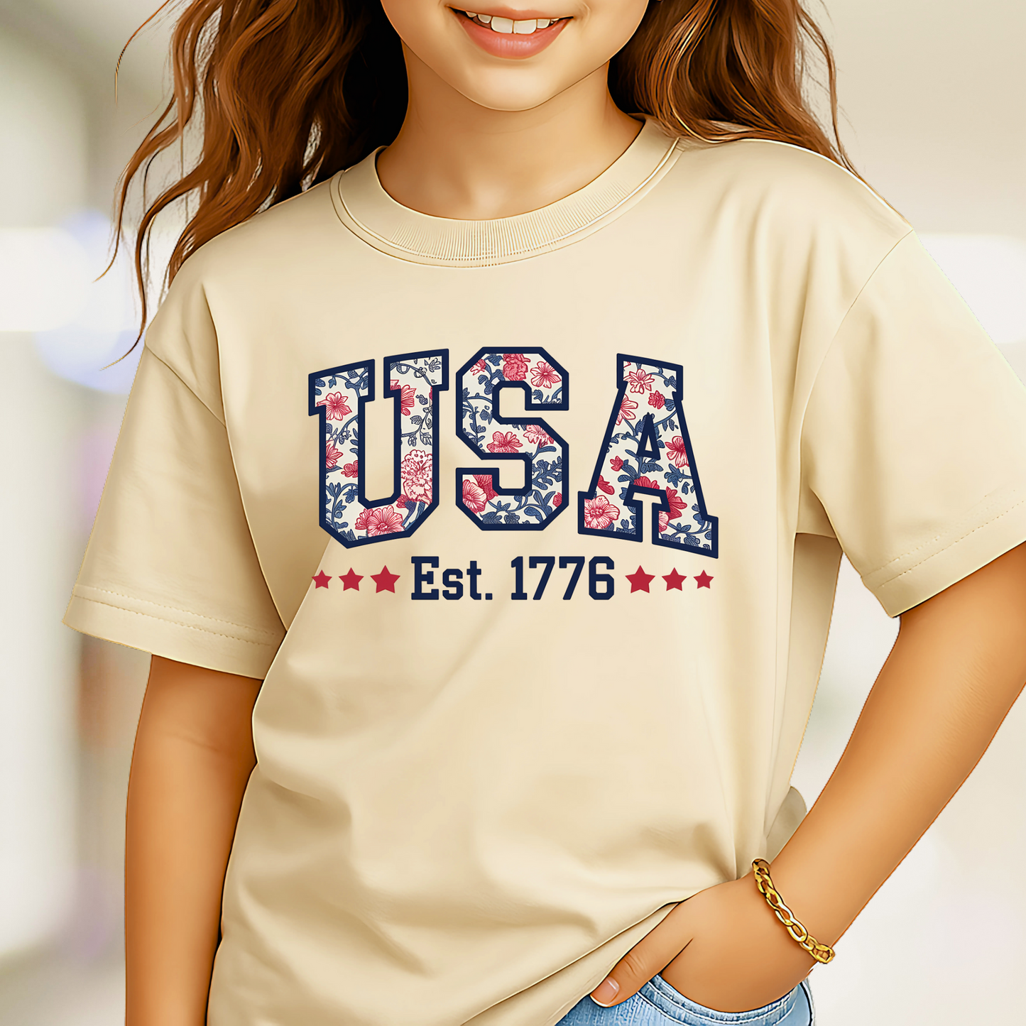 Close-up of beige USA Est. 1776 youth tee on a girl, showing floral patriotic print.