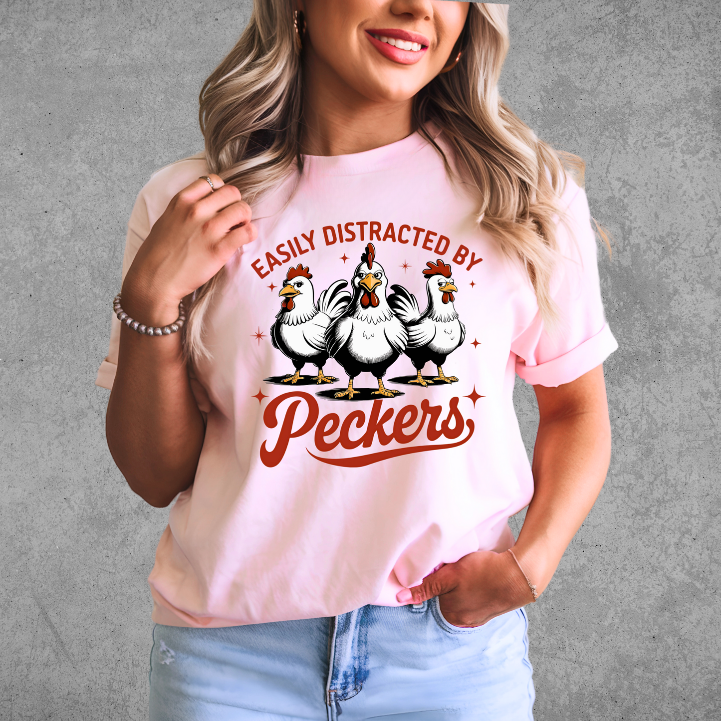 Woman wearing a pink T-shirt with "Easily Distracted by Peckers" text and three funny chickens design. Perfect for chicken lovers and humor enthusiasts