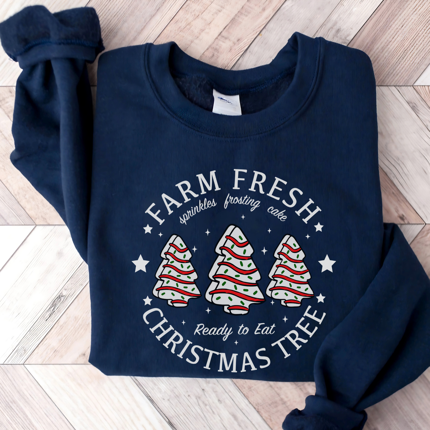 Navy sweatshirt folded with “Farm Fresh Christmas Tree” design featuring frosted tree cakes