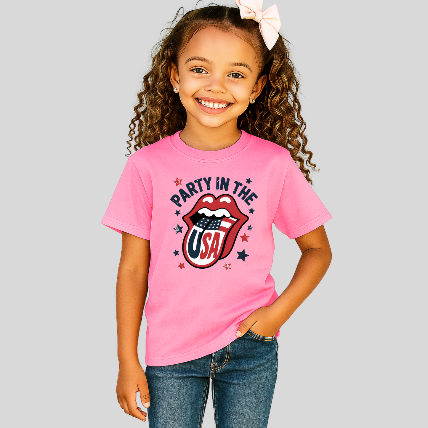 Smiling young girl in pink “Party in the USA” T-shirt with flag lips graphic on plain background. Fun and bold patriotic tee for girls to wear for the 4th of July, family BBQs, or summer vacations.
