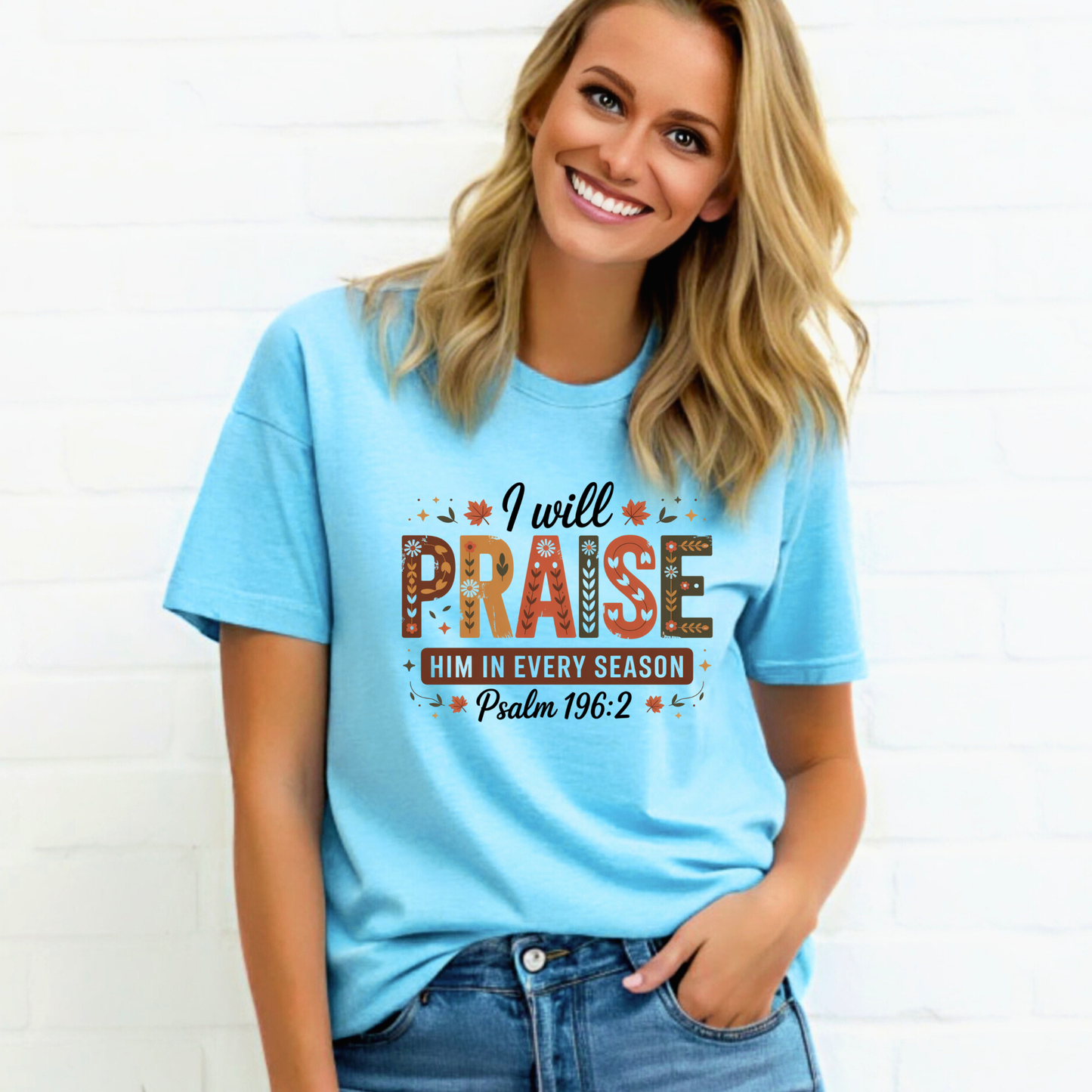 Woman wearing light blue “I Will Praise Him In Every Season” fall T-shirt with autumn colors