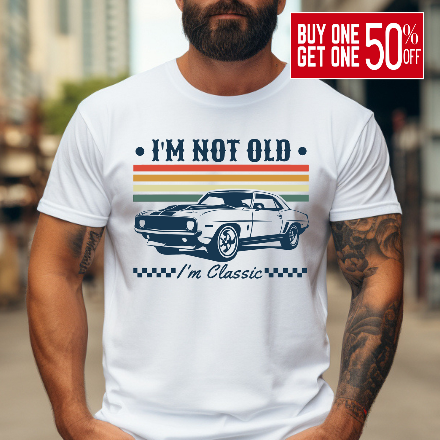 A bearded man wearing a white "I'm Not Old – I'm Classic" T-shirt with a retro muscle car design and vintage racing stripes in orange, yellow, and green. The graphic tee has a bold, nostalgic feel and is perfect for men who love cars and classic style. Great gift idea for car enthusiasts and birthdays.