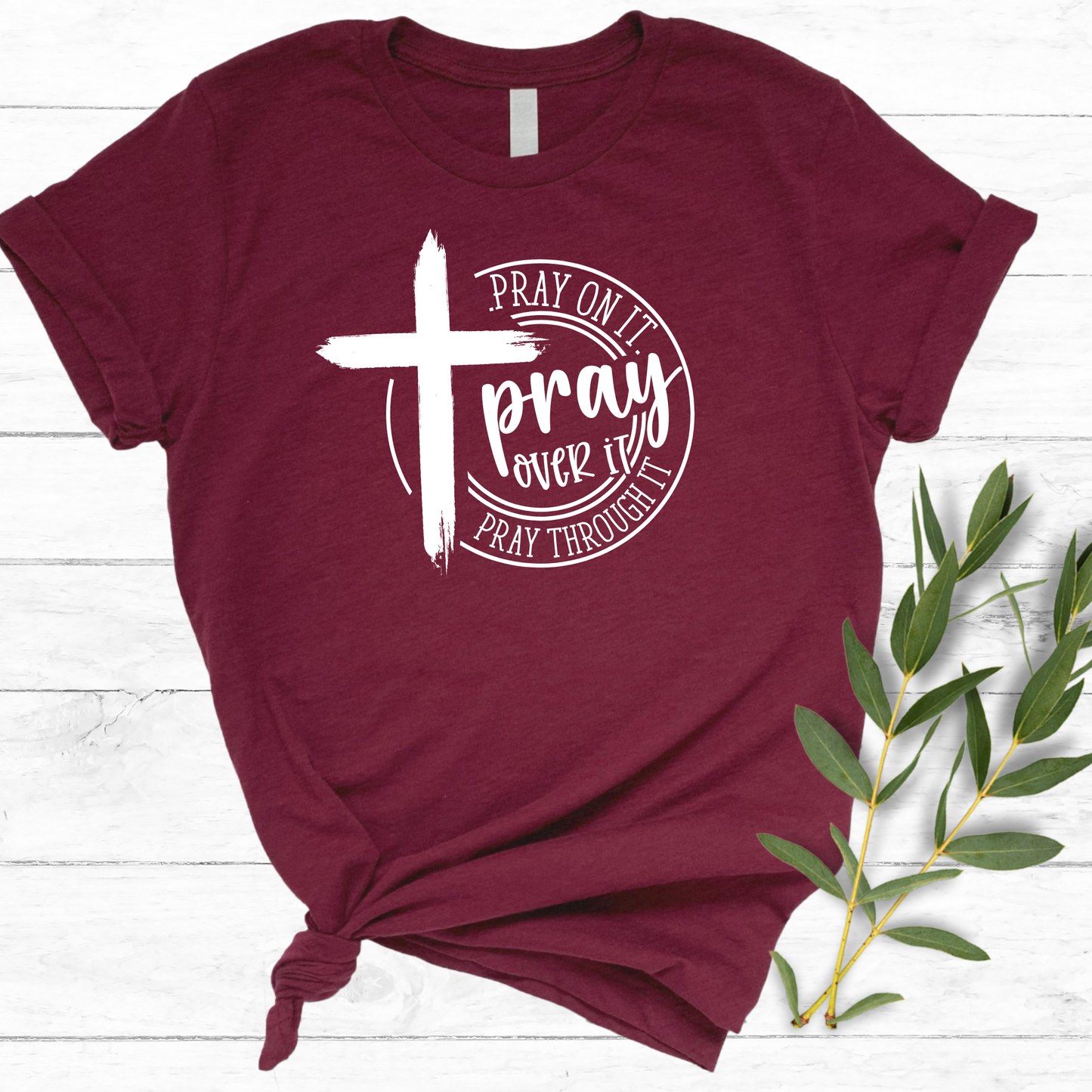 Close-up of a maroon Christian tee with a white cross and ‘Pray Over It’ religious quote