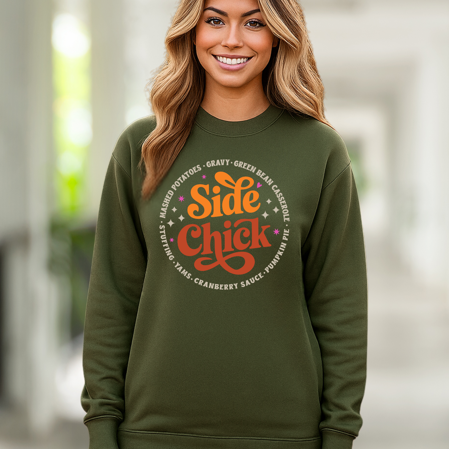 Military green unisex “Side Chick” sweatshirt styled for fall. Woman modeling funny Thanksgiving pullover with retro text featuring side dishes like stuffing, mashed potatoes, and pumpkin pie. Perfect for fall outfits, Friendsgiving, and holiday photos.