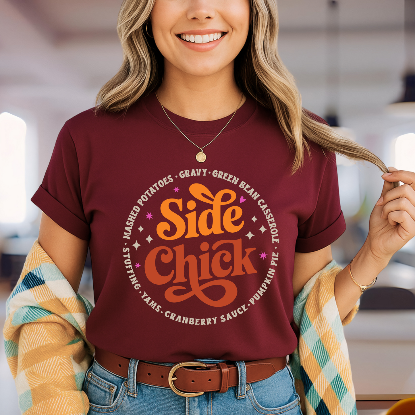 Model wearing an maroon “Side Chick” adult unisex t-shirt with a retro Thanksgiving food graphic. Shirt lists mashed potatoes, stuffing, cranberry sauce, and more. Fun fall fashion for Friendsgiving, holiday baking, or Thanksgiving dinner. Great for women who love cozy and casual autumn style.