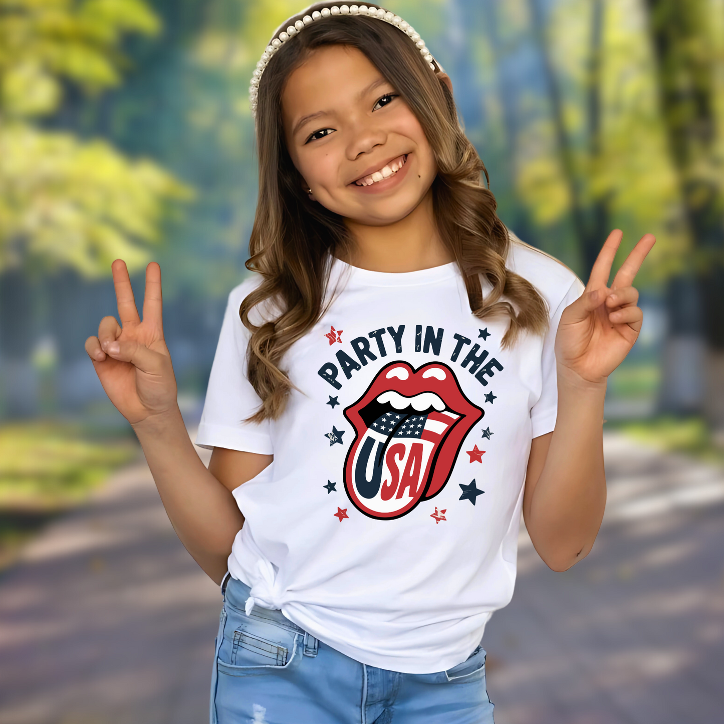 Smiling girl wearing a white “Party in the USA” T-shirt with red lips and American flag design, outdoors with trees in the background. Perfect patriotic shirt for girls celebrating 4th of July, Memorial Day, or any summer event with USA pride.
