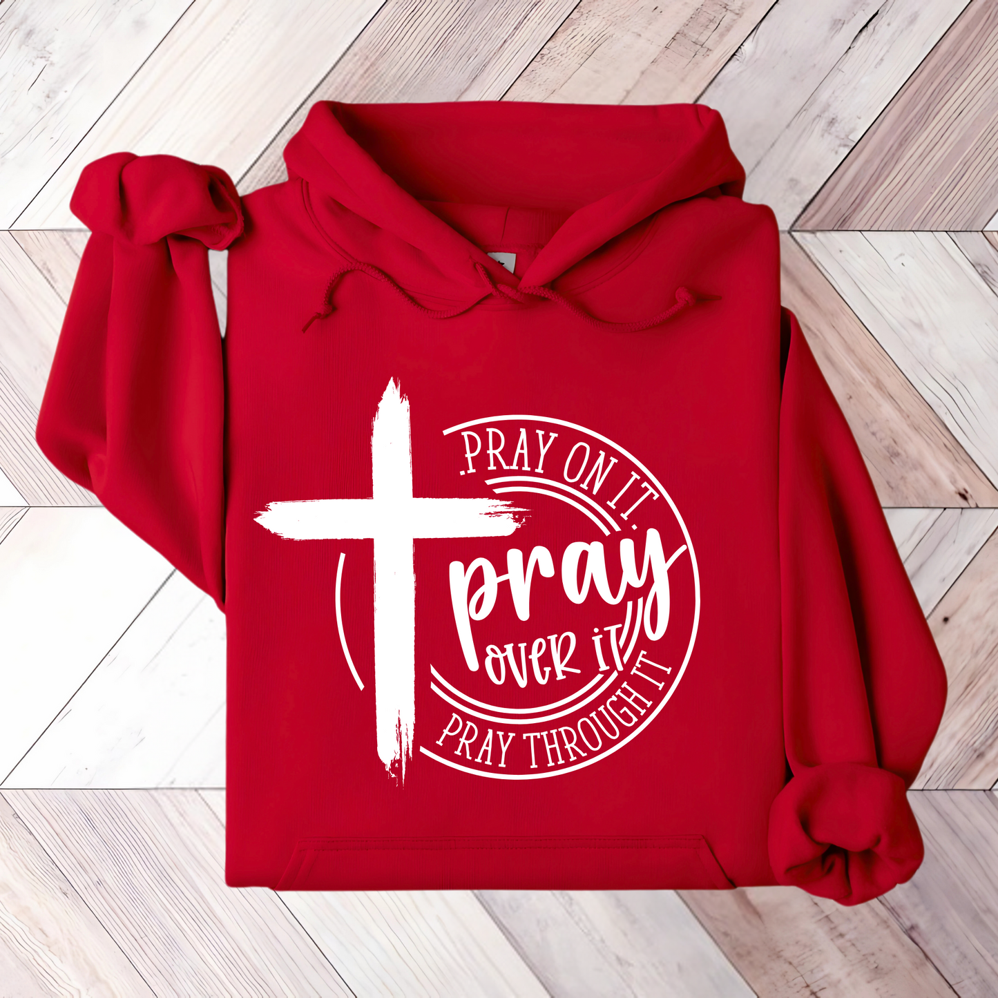 Close-up of a red Christian hoodie with a white cross and ‘Pray Over It’ religious quote.