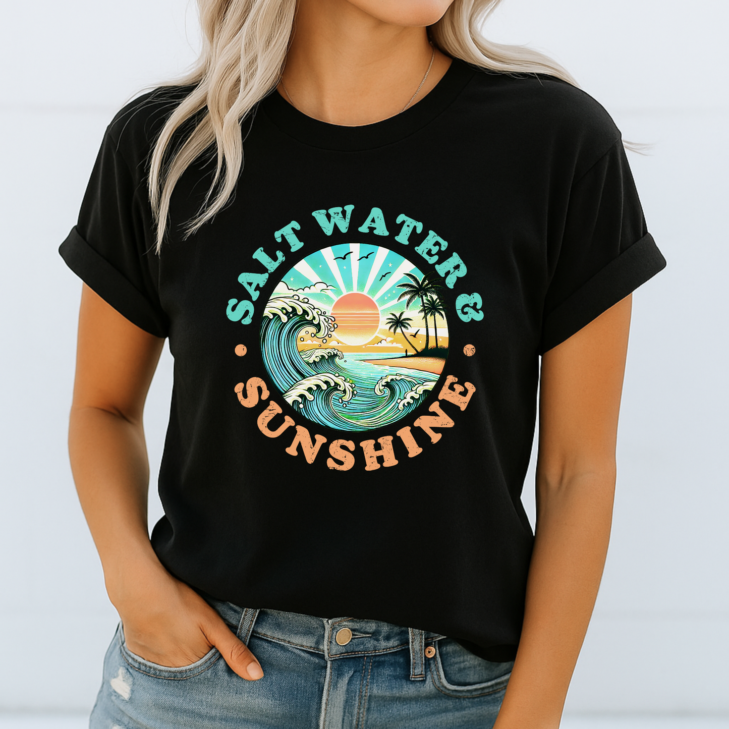 Woman in black Salt Water & Sunshine T-shirt with wave and sunset design, casual summer look