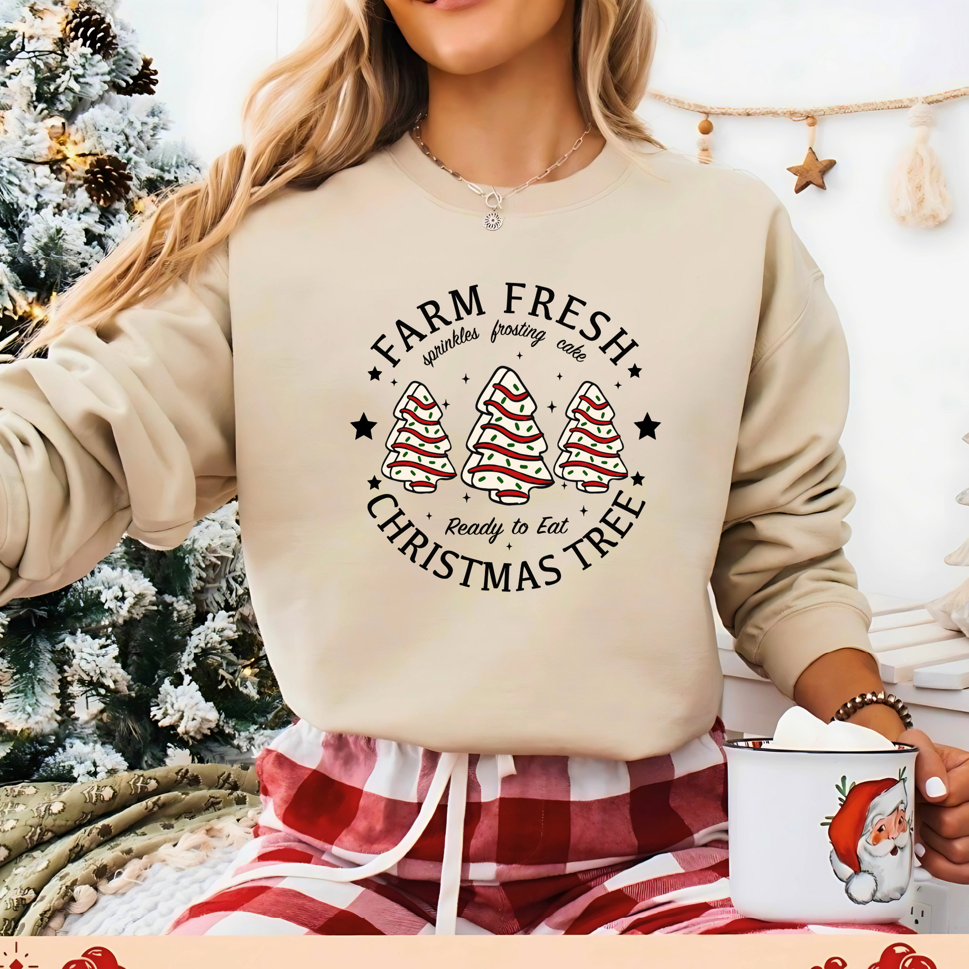 Woman in tan Christmas sweatshirt with frosted tree cakes by a Christmas tree