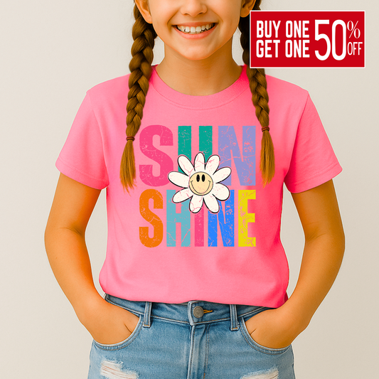 Smiling girl wearing a bright pink Sunshine T-shirt with a retro daisy and rainbow letters