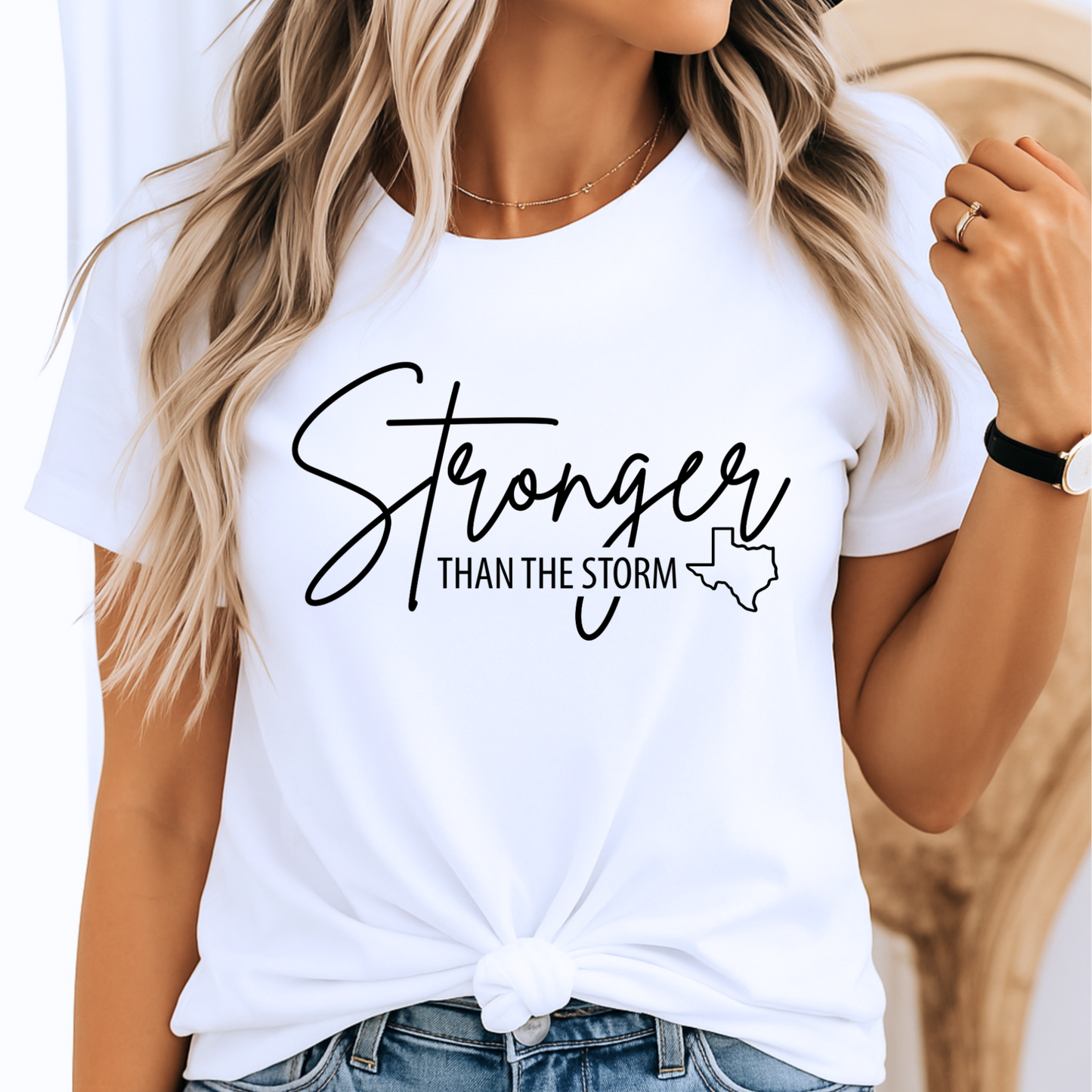 Woman wearing white "Stronger Than the Storm" Texas T-shirt with black text and state outline, flood relief support graphic tee for women, knotted front style
