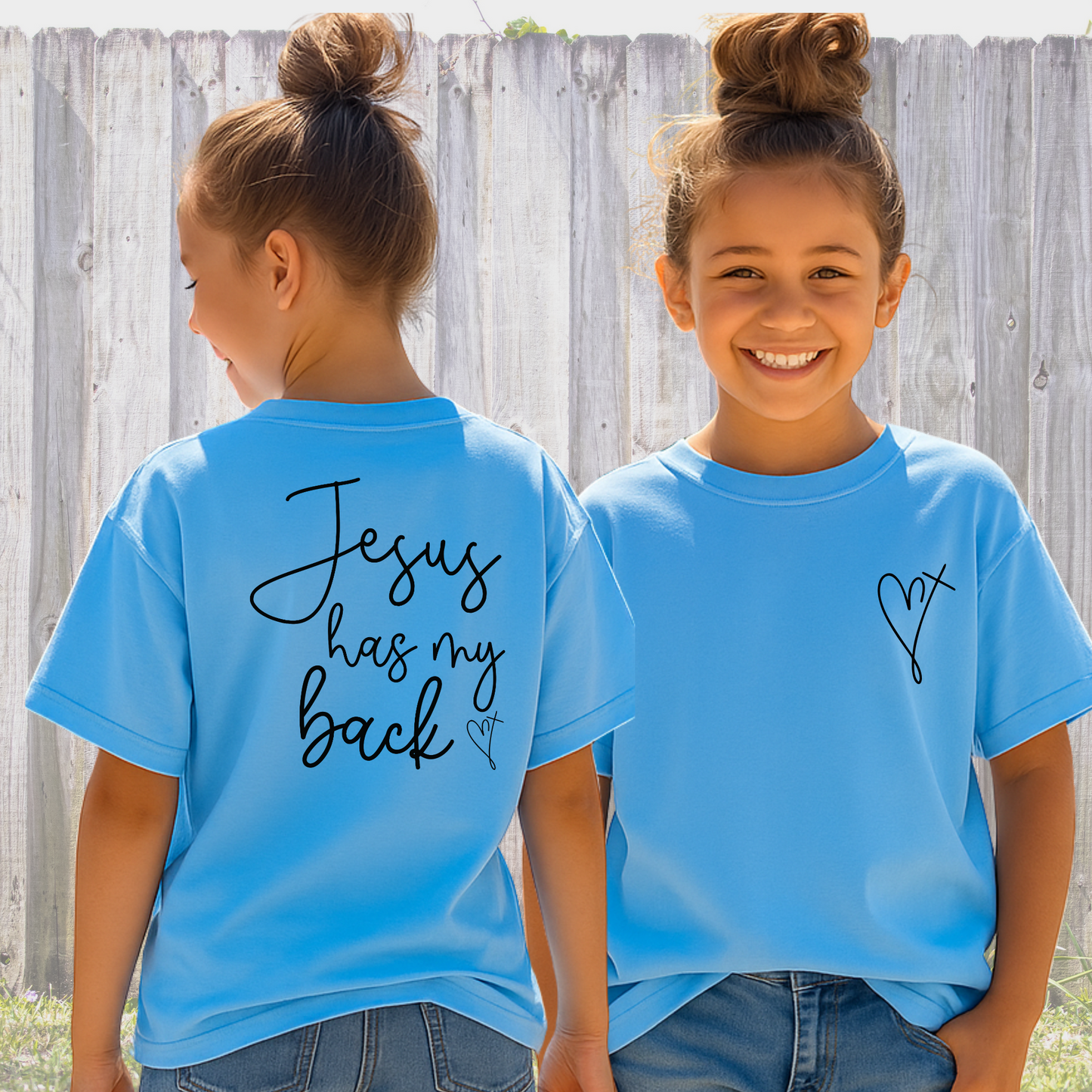 Two girls wearing blue t-shirts with text, standing in front of a wooden fence.