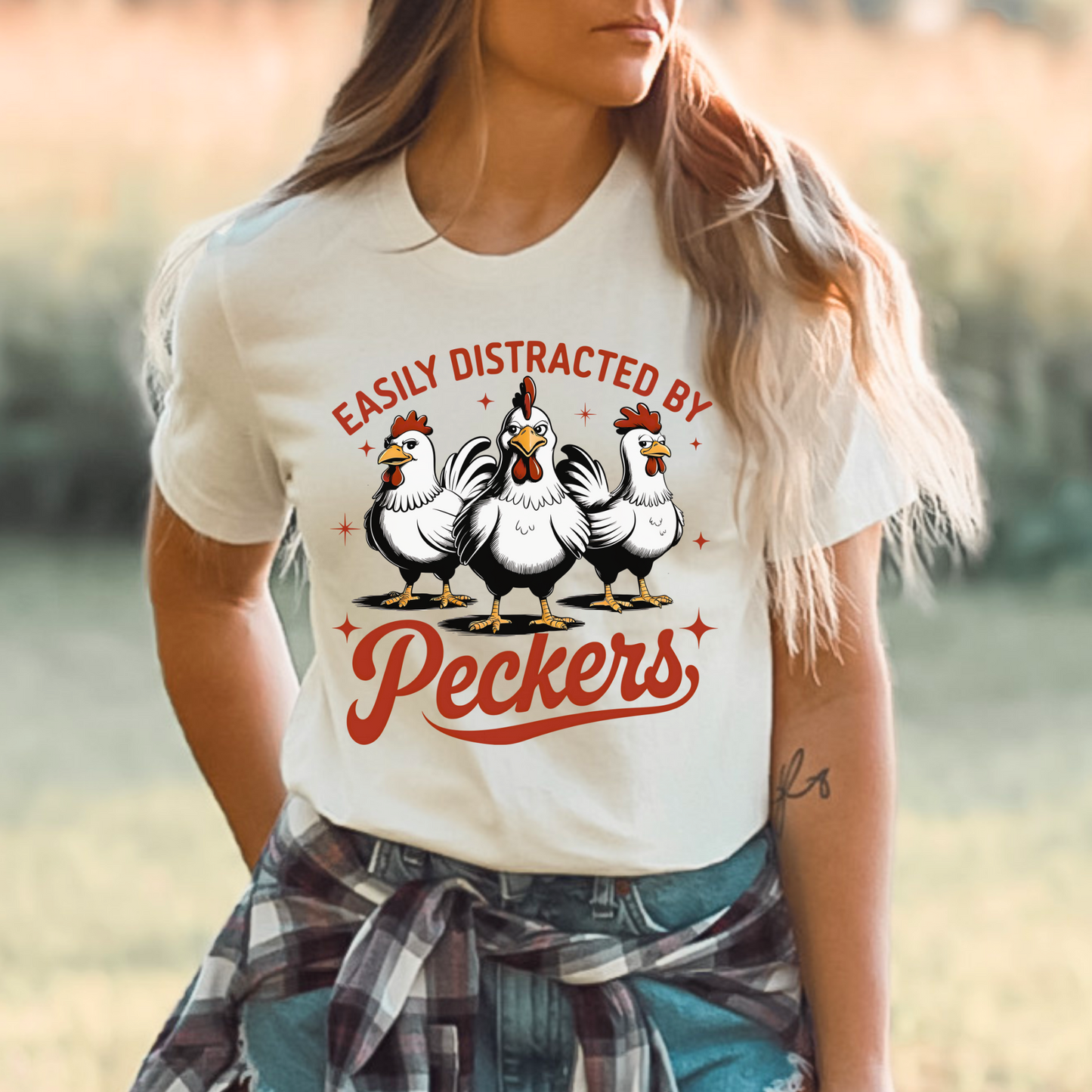 Country Woman wearing a T-shirt with "Easily Distracted by Peckers" text and three funny chickens design. Perfect for chicken lovers and humor enthusiasts