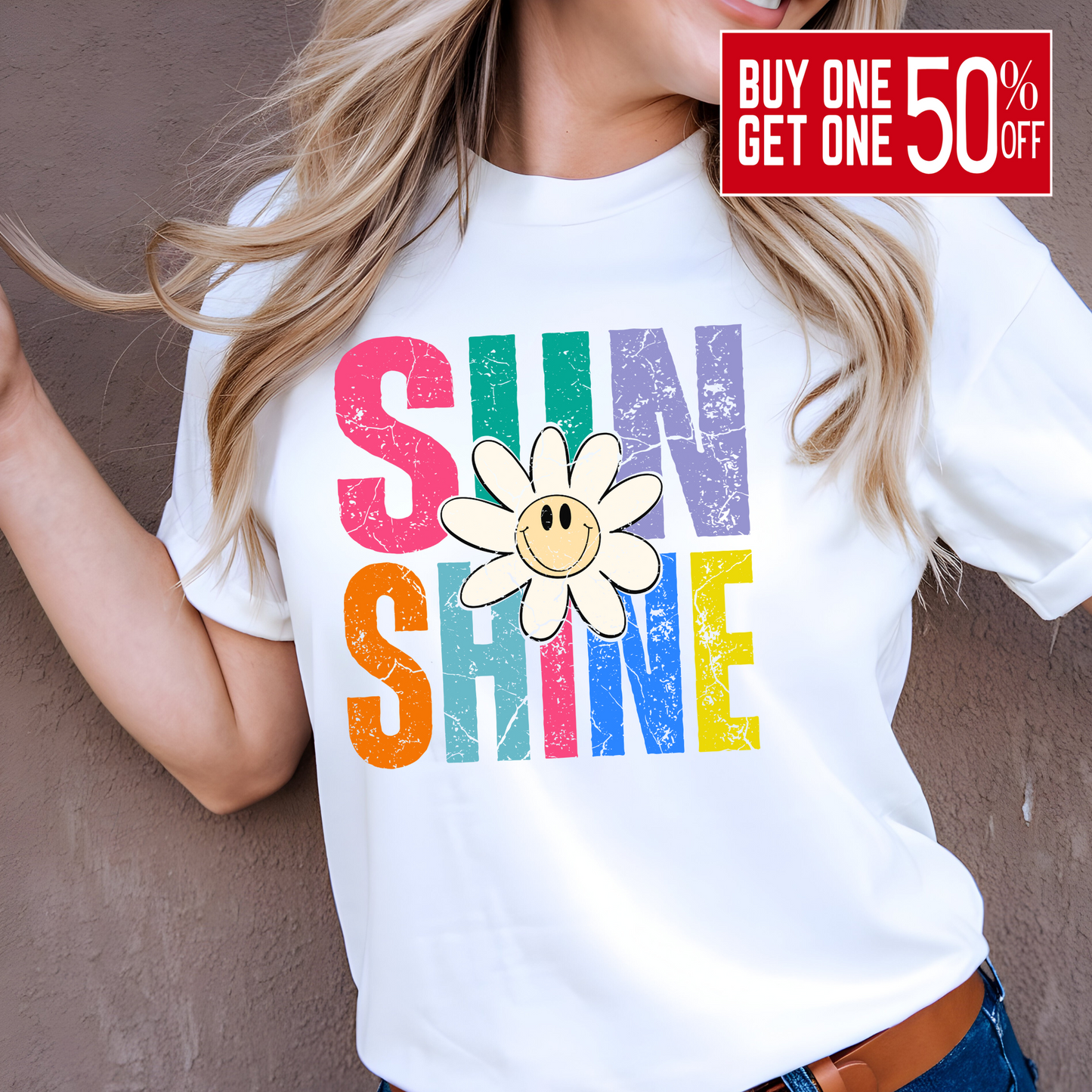Woman wearing white shirt with rainbow “SUNSHINE” and smiley daisy
