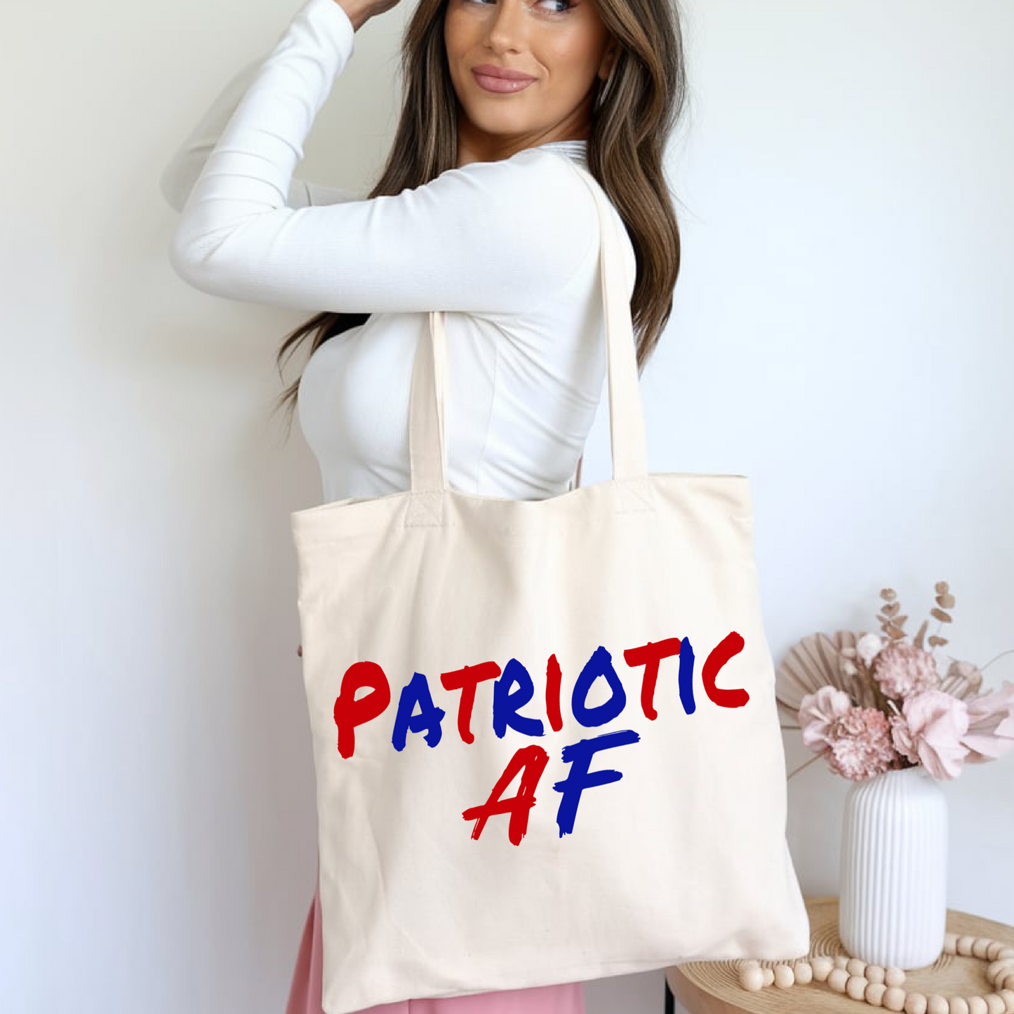 Woman holding canvas tote bag with bold red and blue 'Patriotic AF' text