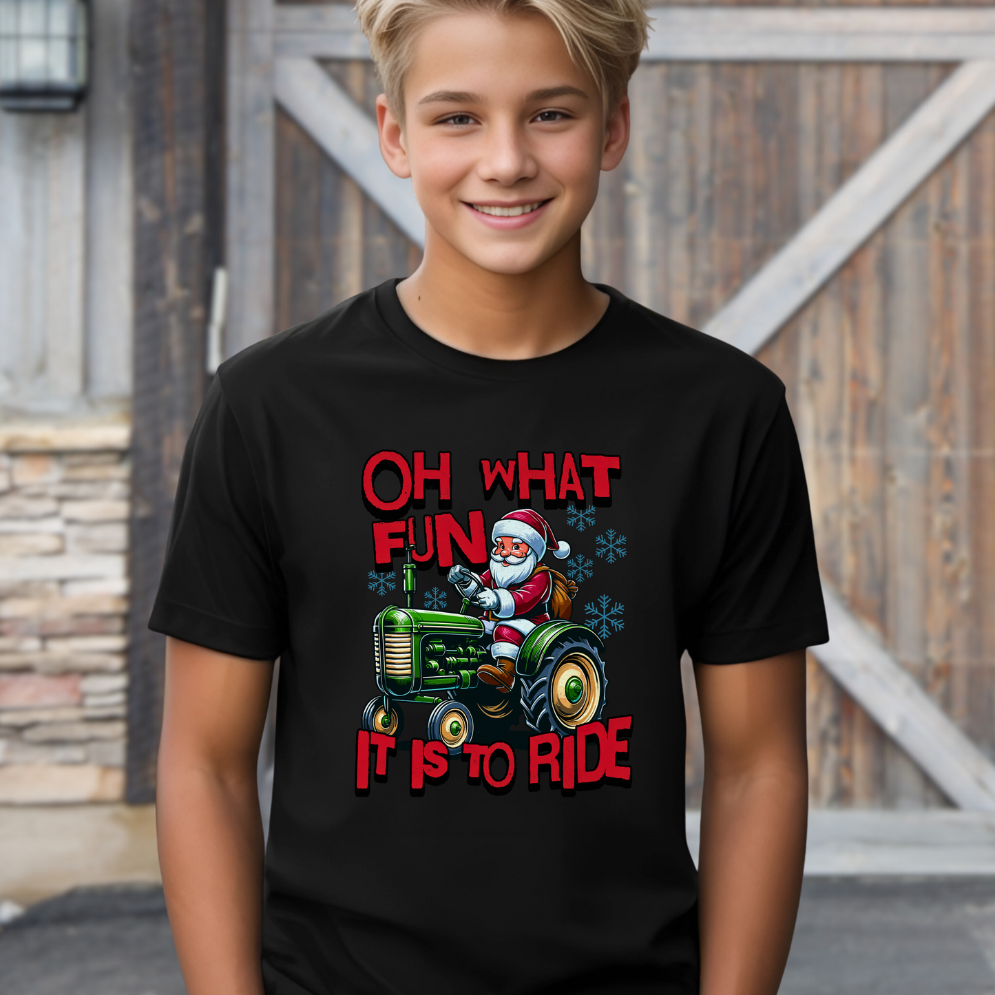 outh boy in black holiday T-shirt with Santa Claus on a green tractor and red festive lettering.