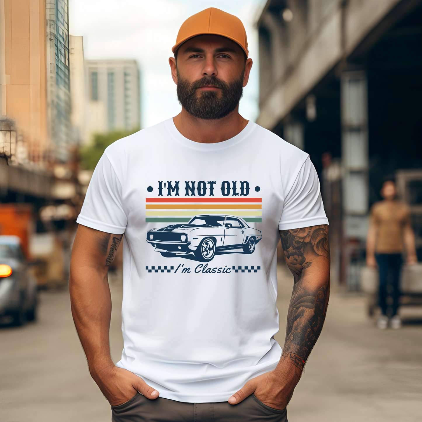 Man standing outdoors in a white graphic tee with orange hat. The shirt reads “I’m Not Old – I’m Classic” and shows a retro muscle car with colorful stripes. A great choice for men who enjoy vintage style and classic cars.