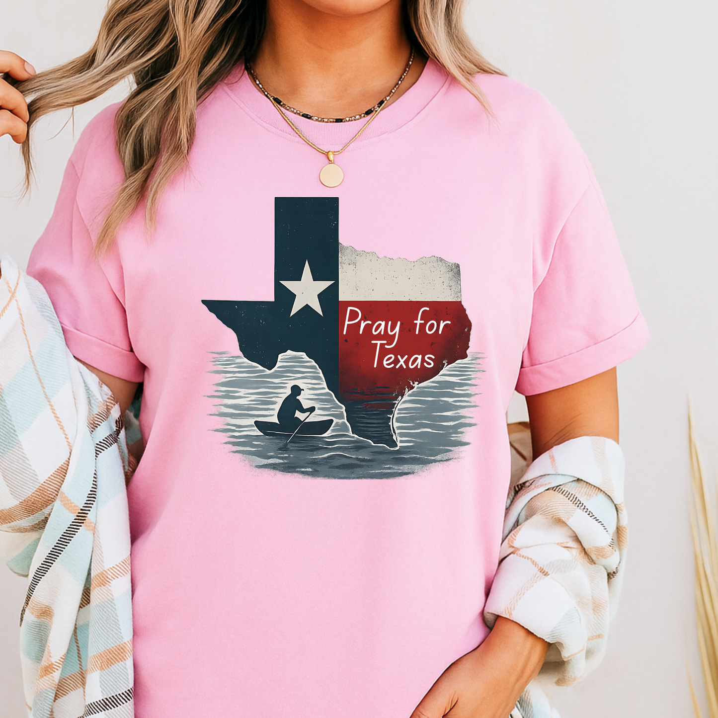 Pink Pray for Texas T-shirt in a unisex fit, with a distressed Texas flag design and canoe silhouette graphic. Styled with casual plaid outerwear, perfect for everyday Texas pride fashion.