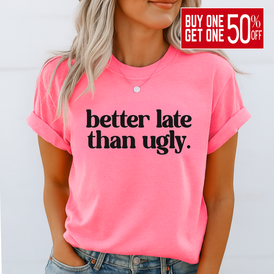 Person wearing a pink t-shirt with 'better late than ugly' text on a white background