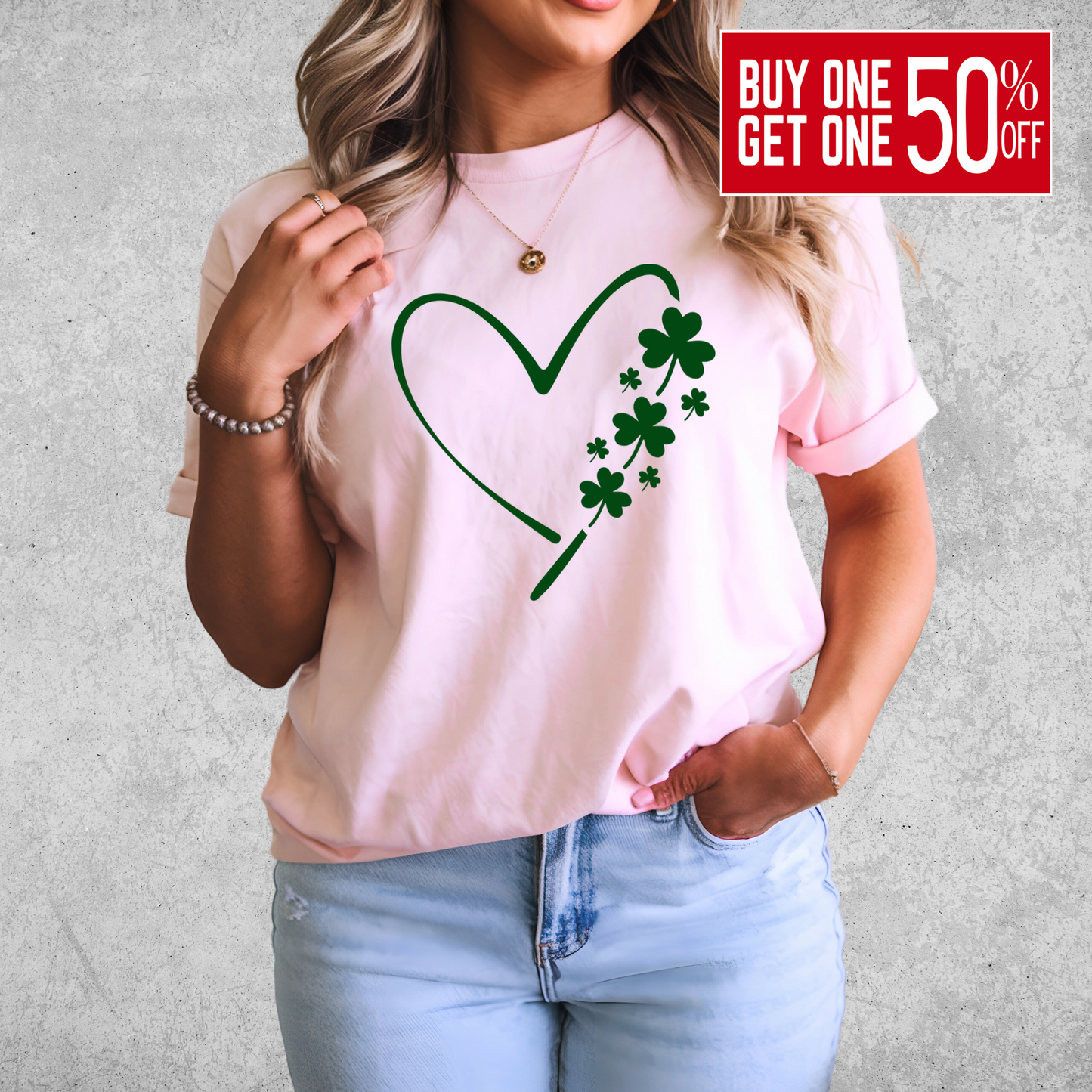A woman wearing a pink T-shirt with a minimalist green heart and shamrock design, perfect for St. Patrick’s Day celebrations.