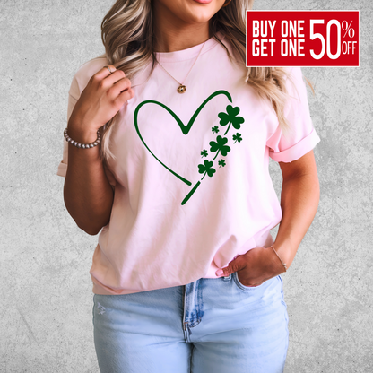A woman wearing a pink T-shirt with a minimalist green heart and shamrock design, perfect for St. Patrick’s Day celebrations.