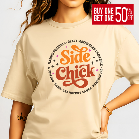 Adult woman modeling a sand-colored “Side Chick” t-shirt featuring festive side dish design in warm fall tones. The perfect neutral tee for Thanksgiving or Friendsgiving gatherings. Soft cotton blend with a relaxed unisex fit for comfort and style all season long.