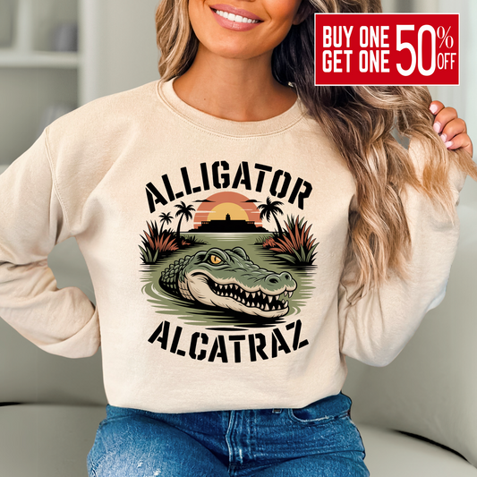 Woman wearing sand colored Alligator Alcatraz sweatshirt with bold alligator and sunset island graphic, cozy women’s casual pullover for travel or lounging