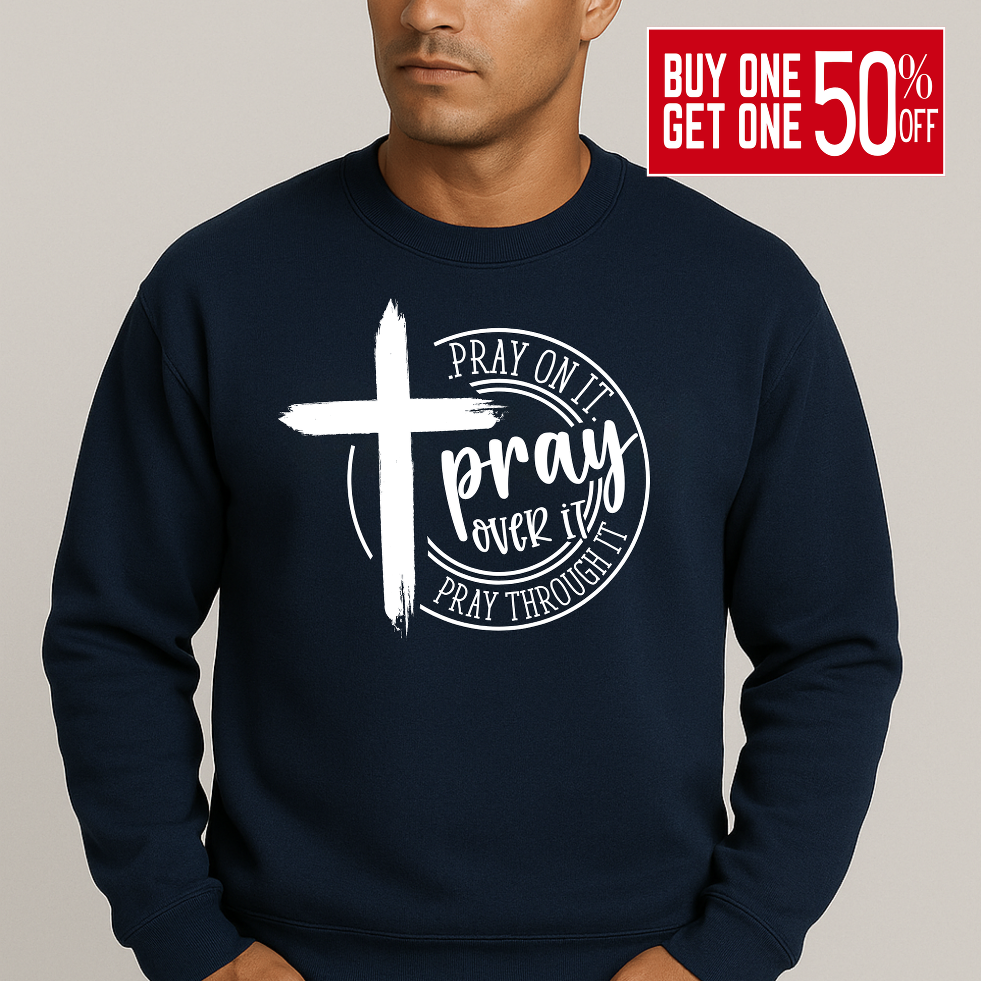 Man wearing an navy sweatshirt with a bold white cross and text: "Pray On It, Pray Over It, Pray Through It"