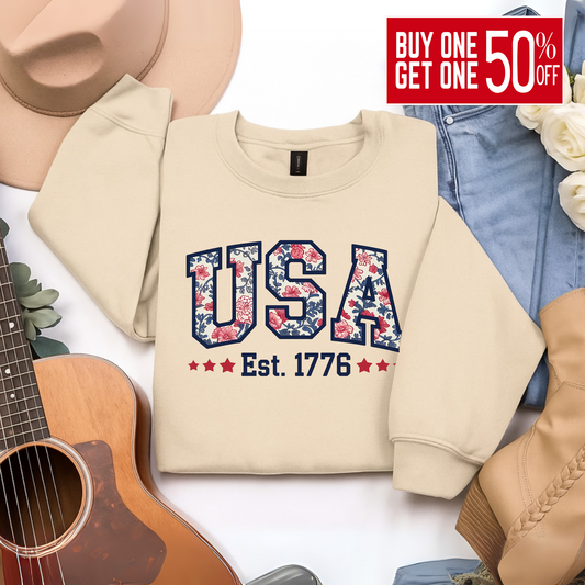 Sand beige floral USA sweatshirt – styled flat lay with jeans and western accessories.

