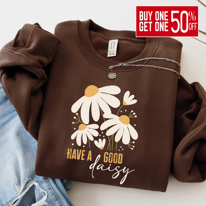 Chocolate brown “Have a Good Daisy” sweatshirt folded with jeans and a necklace, featuring a cozy fall floral graphic perfect for seasonal outfits, pumpkin patch days, or casual autumn layering.
