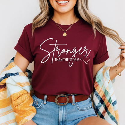 Maroon "Stronger Than the Storm" women's Texas faith T-shirt with white script text and state silhouette, styled with fall flannel.