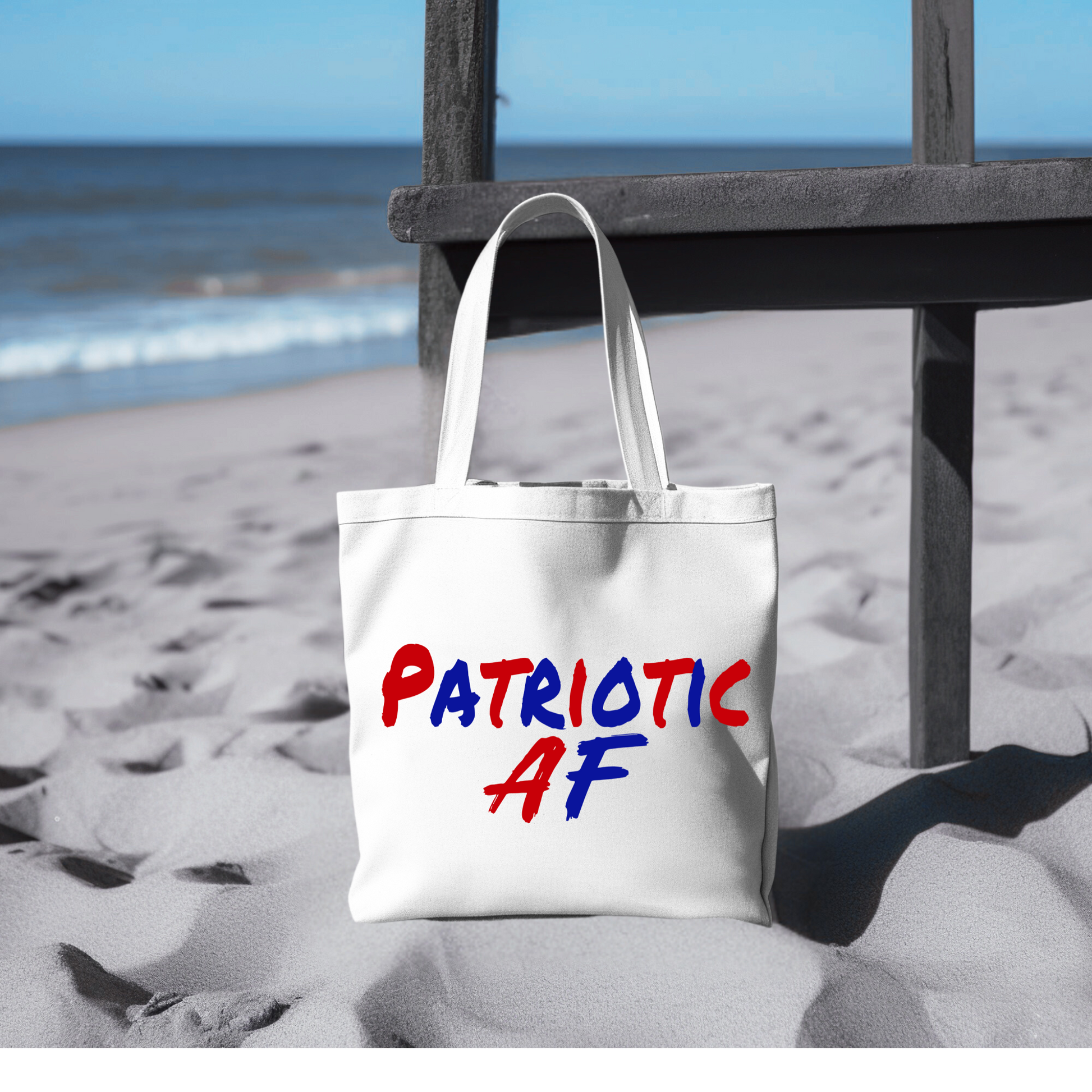 Patriotic AF beach tote bag on sand with ocean background