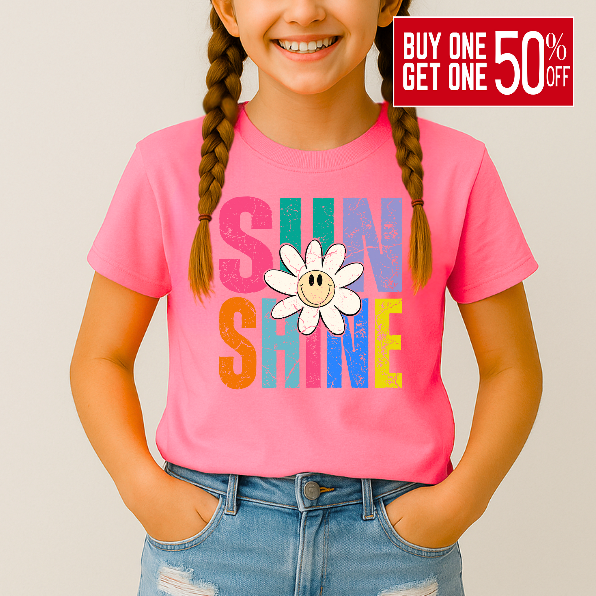 Smiling girl wearing a bright pink Sunshine T-shirt with a retro daisy and rainbow letters

