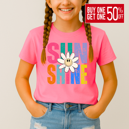 Smiling girl wearing a bright pink Sunshine T-shirt with a retro daisy and rainbow letters

