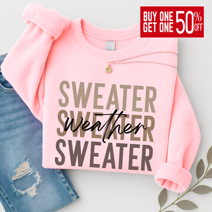“Light pink Sweater Weather sweatshirt folded with necklace and jeans. A cozy and stylish unisex crewneck perfect for women’s fall outfits and winter layering.