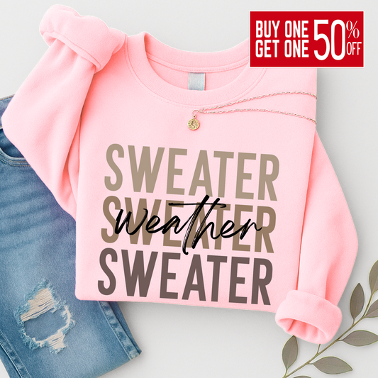 “Light pink Sweater Weather sweatshirt folded with necklace and jeans. A cozy and stylish unisex crewneck perfect for women’s fall outfits and winter layering.