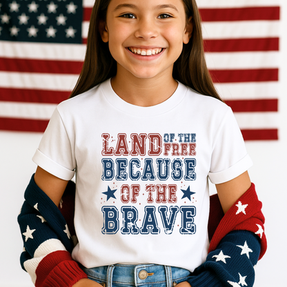 Tween girl smiling in a white "Land of the Free Because of the Brave" shirt with rolled sleeves and red-white-blue cardigan.