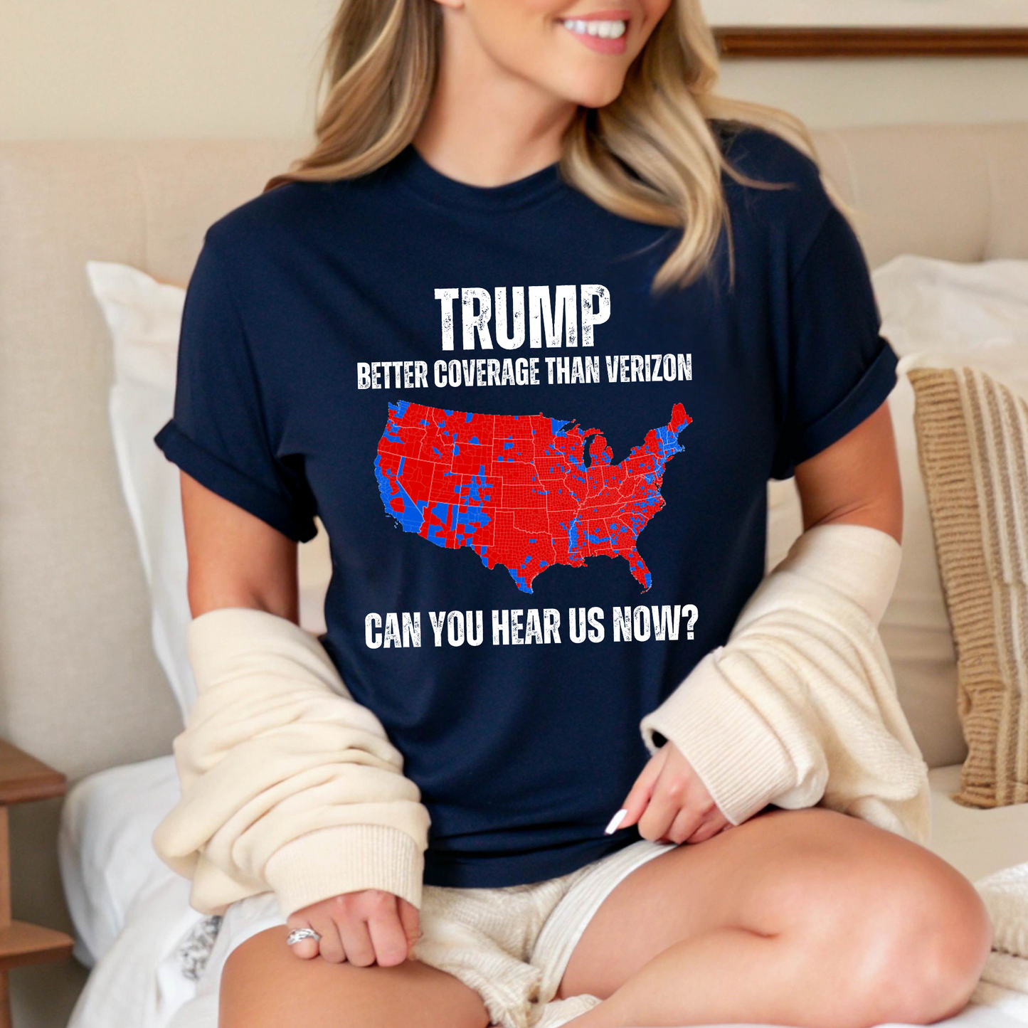 Woman sitting on bed in navy Trump graphic tee with cardigan