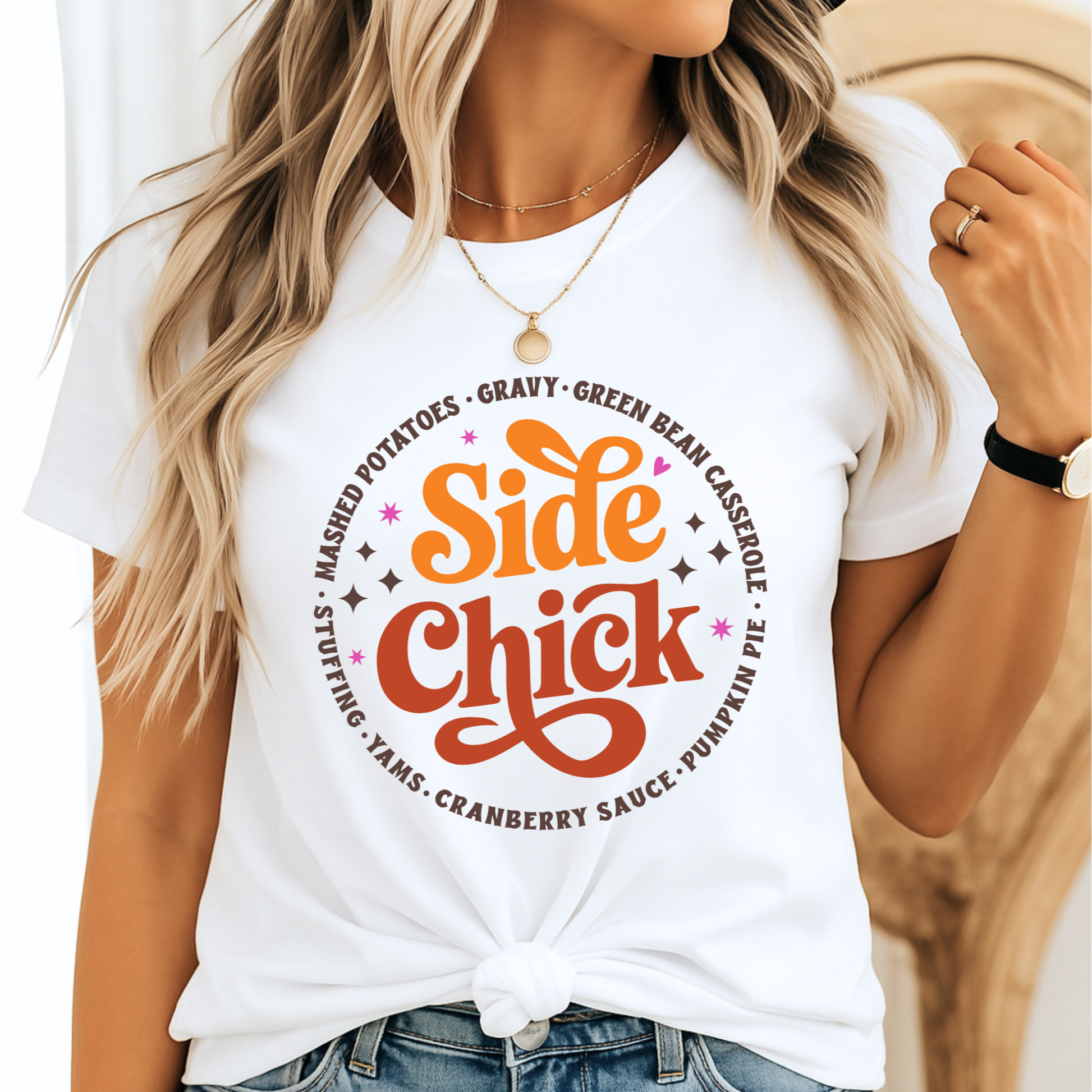 Woman wearing a white “Side Chick” Thanksgiving t-shirt featuring retro fall colors and funny holiday text. Styled with denim jeans and layered jewelry. Perfect for cozy fall family photos, Friendsgiving, and holiday gatherings. Ideal for women and teens who love Thanksgiving side dishes and humorous seasonal fashion.