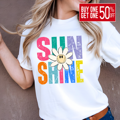 Woman wearing white shirt with rainbow “SUNSHINE” and smiley daisy