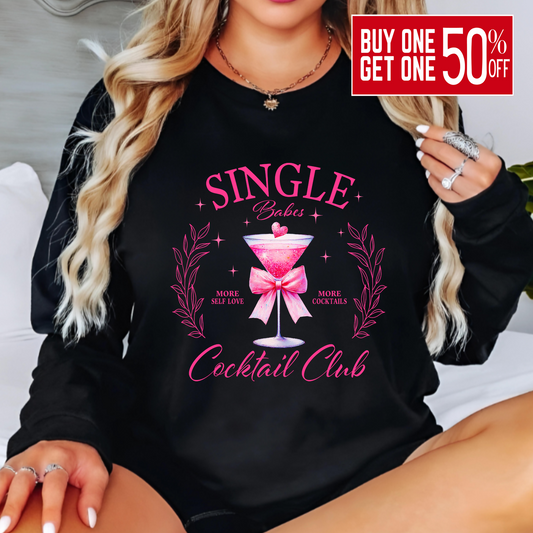 Person wearing a black sweatshirt with pink 'Single Babes Cocktail Club' design.